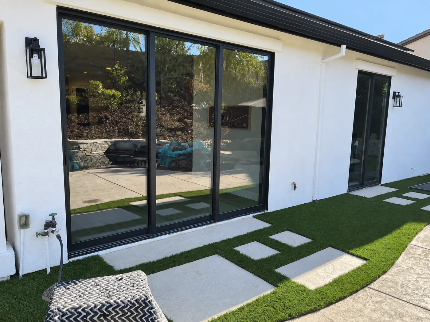Black-framed sliding glass doors installed along a white home exterior