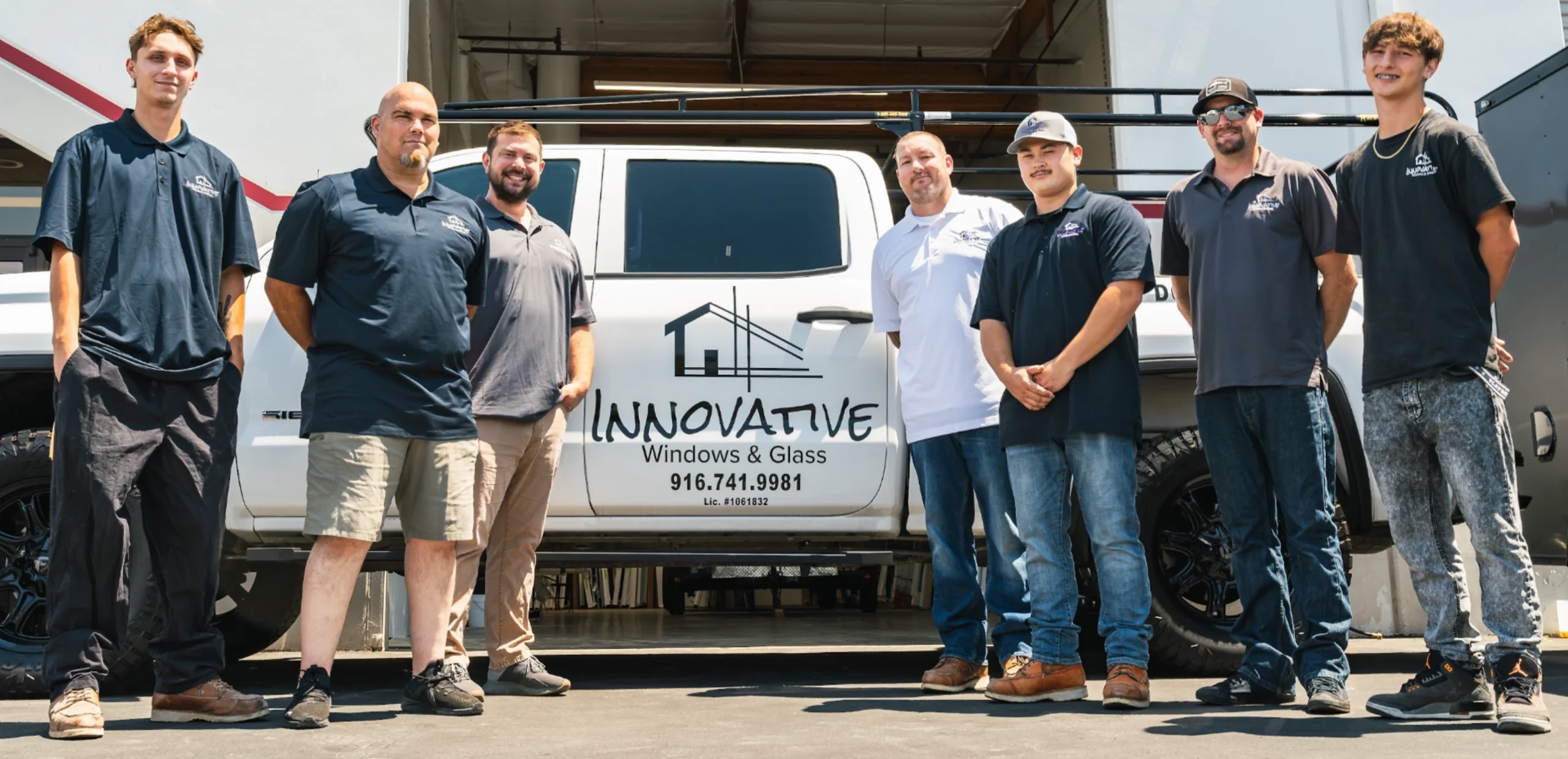 Seven Innovative Windows and Glass team members standing beside their branded white work truck