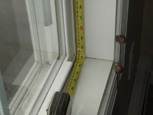 Close‑up photo of double‑glazed window units being measured during installation.